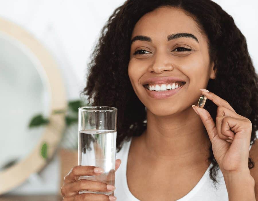 a woman holding a pill and a glass of water